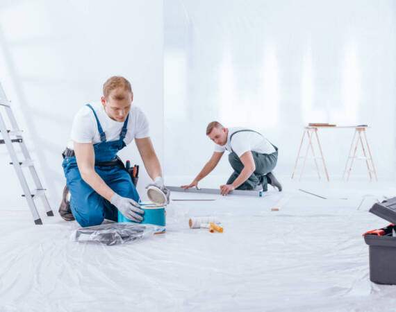 Painter kneeling and opening a can of paint during interior finishing work