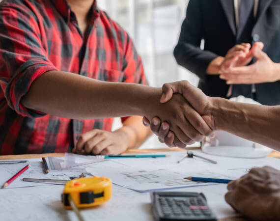 Engineer construction worker team handshake after consultation meeting start up plan new project contract in office center at construction site, teamwork, partnership concept.